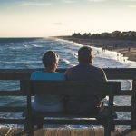 Elderly Couple Sitting on a bench watching sunset