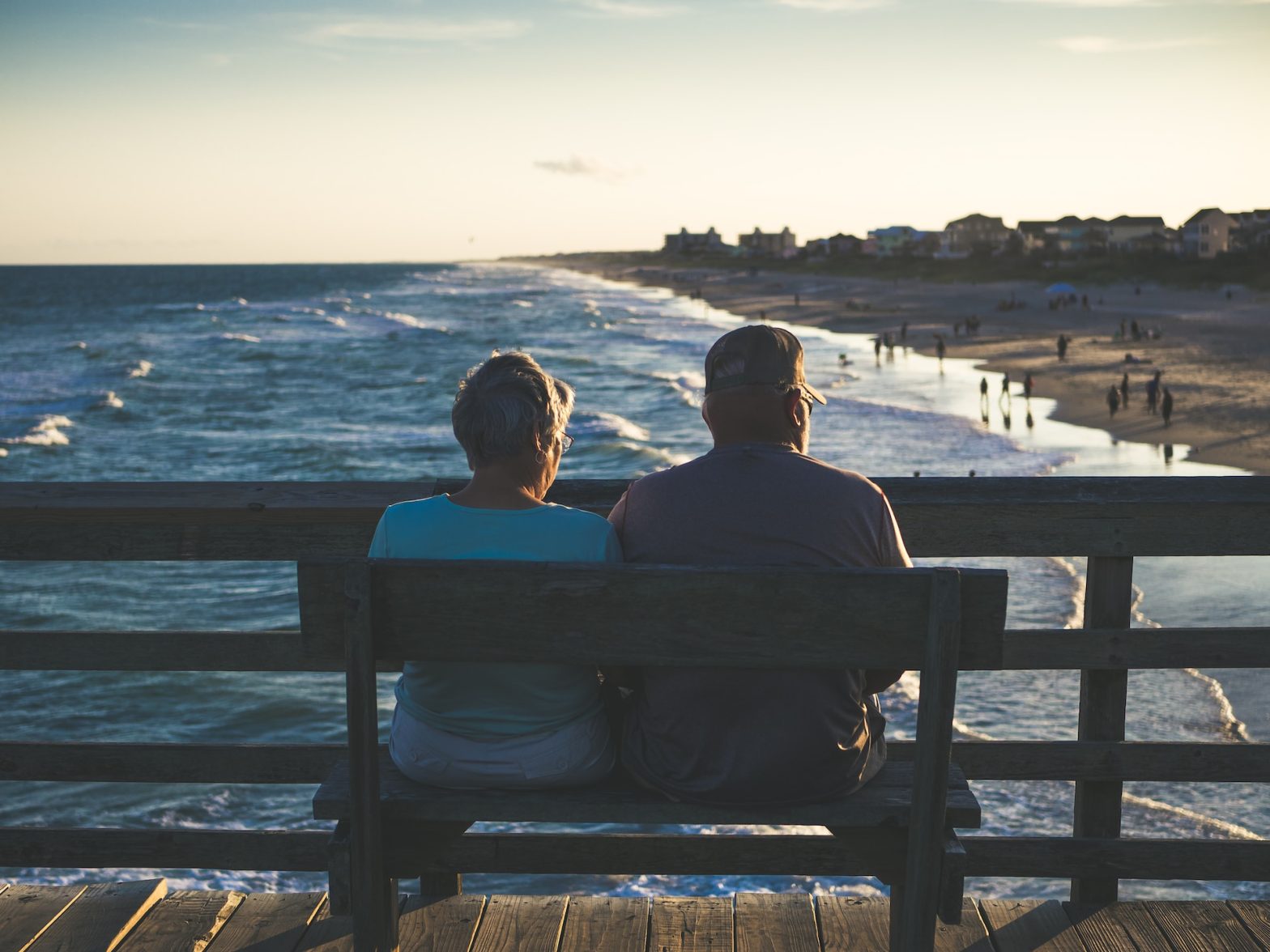 Elderly Couple Sitting on a bench watching sunset