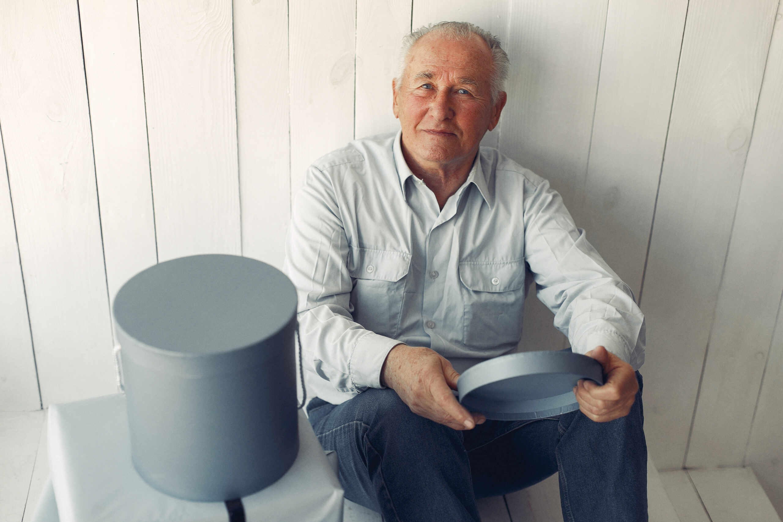 Older man sitting at home opening a present.