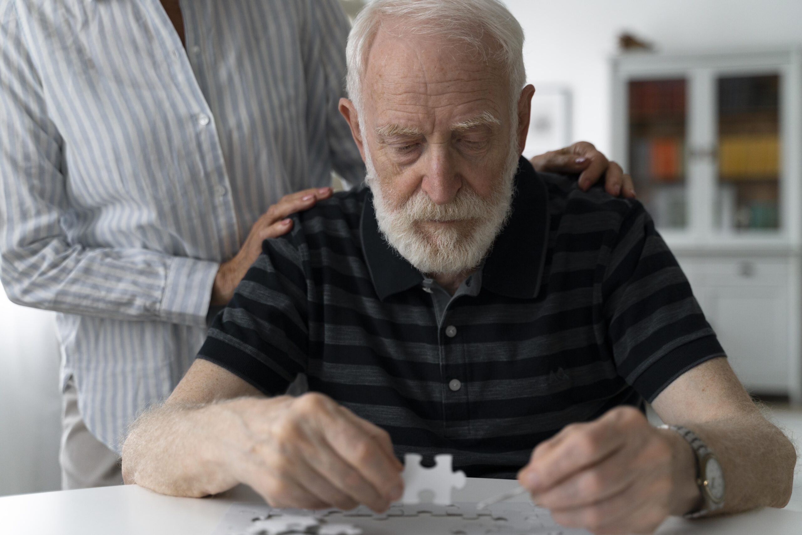 Senior man with dementia working on a puzzle. 